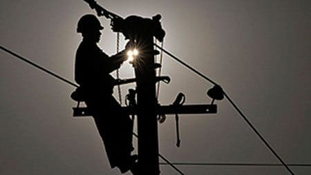 Technicien en train de réparer une panne sur un poteau électrique